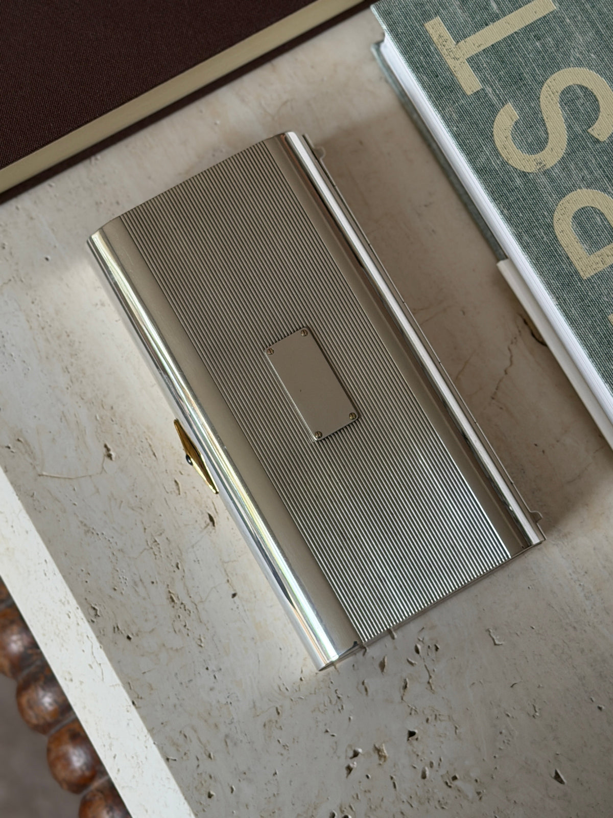 Overhead view of the wood cap end and gold clasp on the Cartier box, styled beside books
