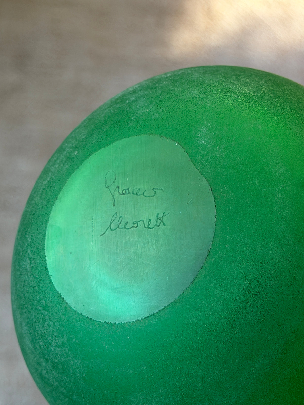 Base of the green vanity bottle showing the engraved Franco Moretti signature on the smooth polished center