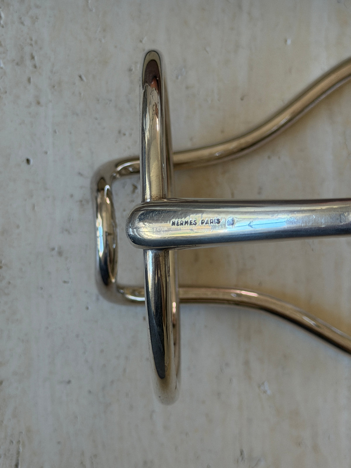 Close view of the wine caddy snaffle bar stamped HERMES PARIS, the polished ring passing through the cheek piece