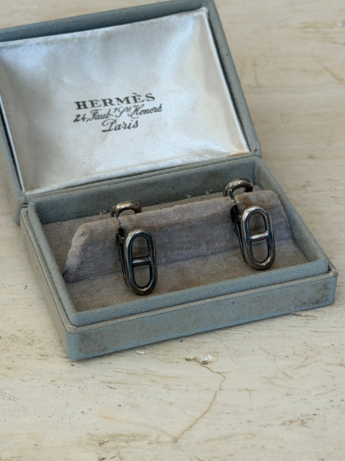 Front view of the original Hermes box holding both anchor chain cufflinks upright on the cushion