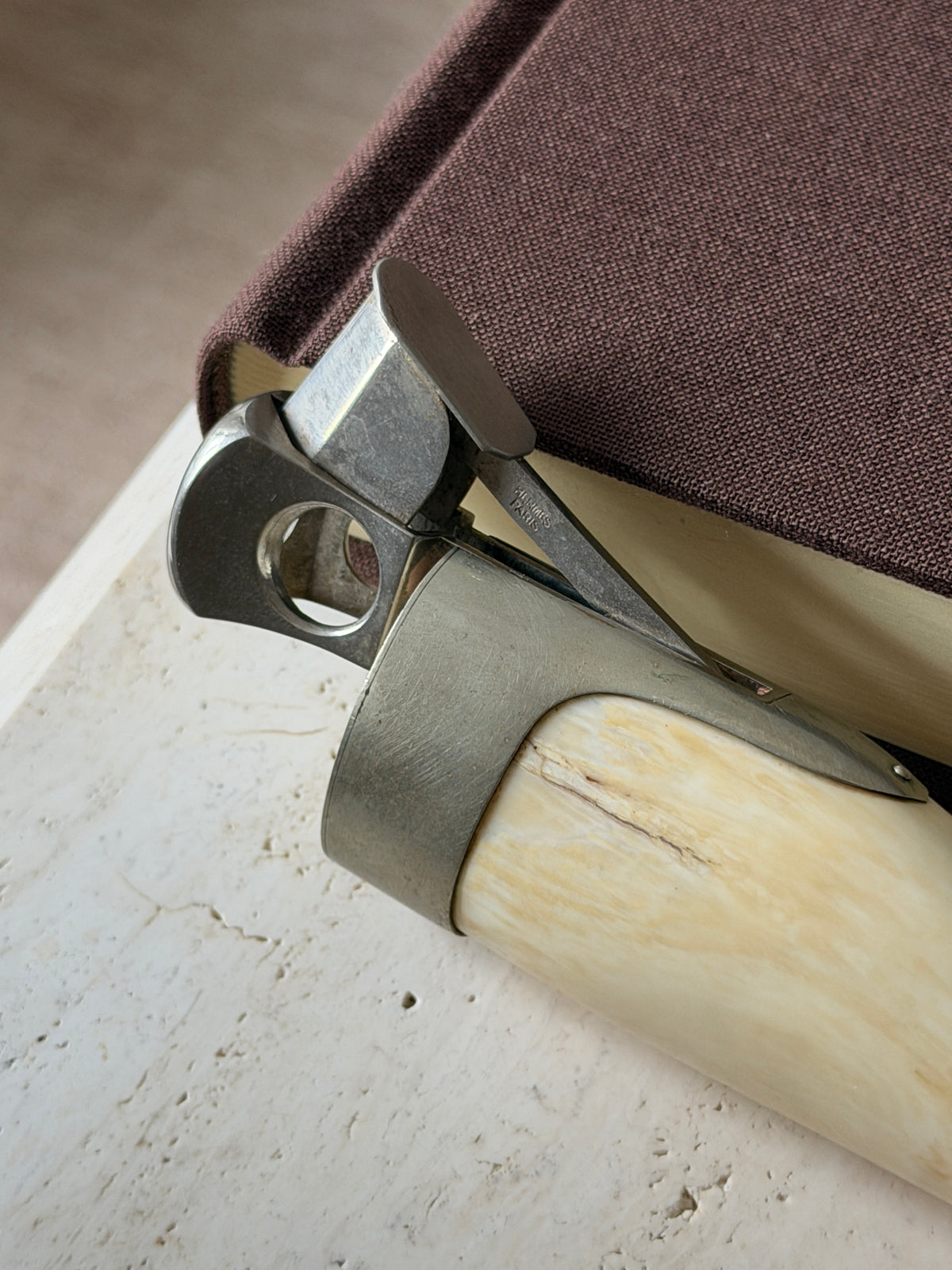 Close detail of the Hermes cigar cutter mechanism, the HERMES PARIS stamp on the steel lever beside the round cutting hole