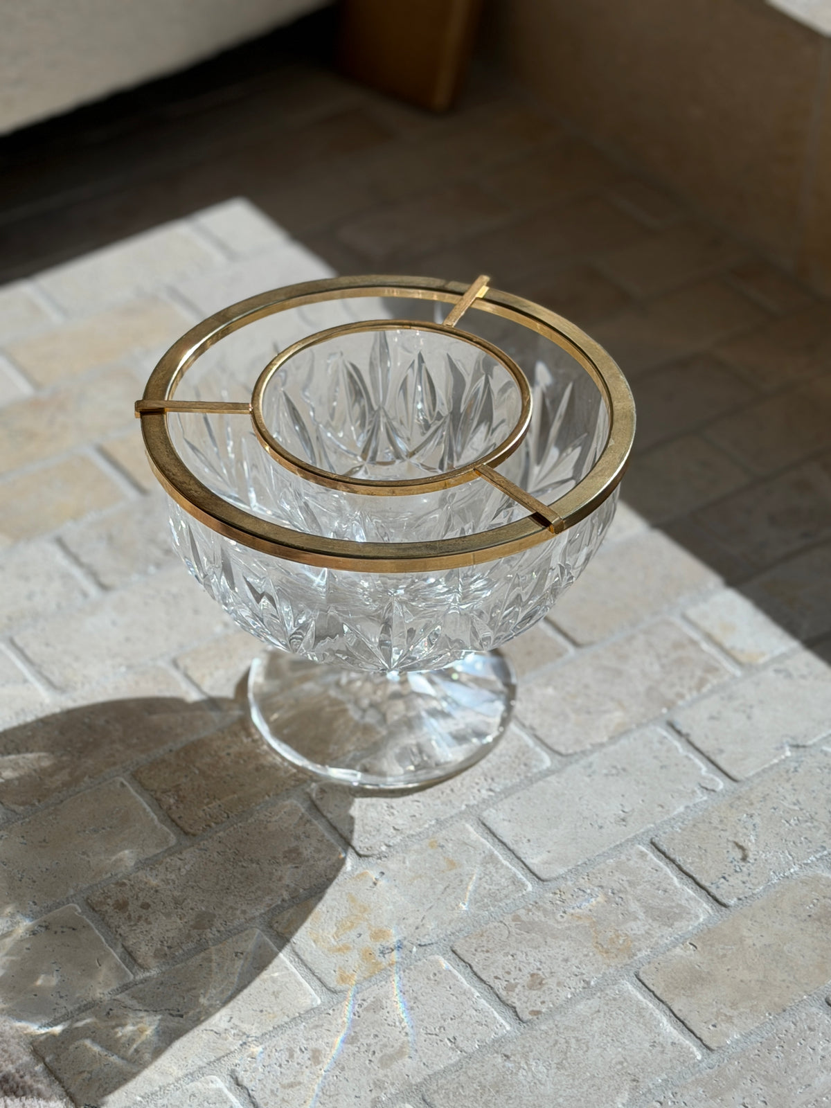 Angled view of the English cut crystal caviar dish, the gilt bridge bars suspending the inner bowl above the outer ice well