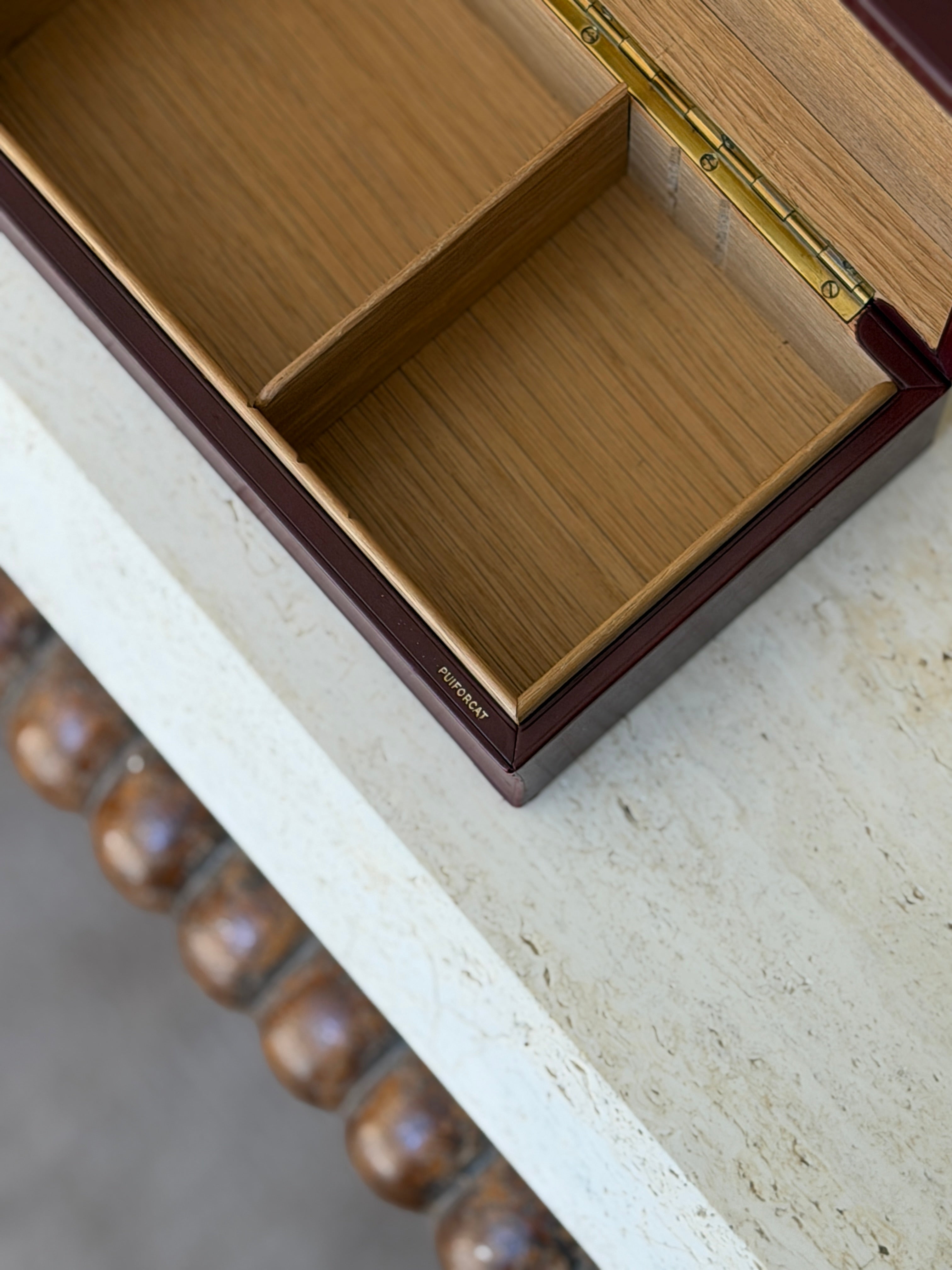Close-up detail view of open Puiforcat red leather box showing dual-compartment wood lined interior