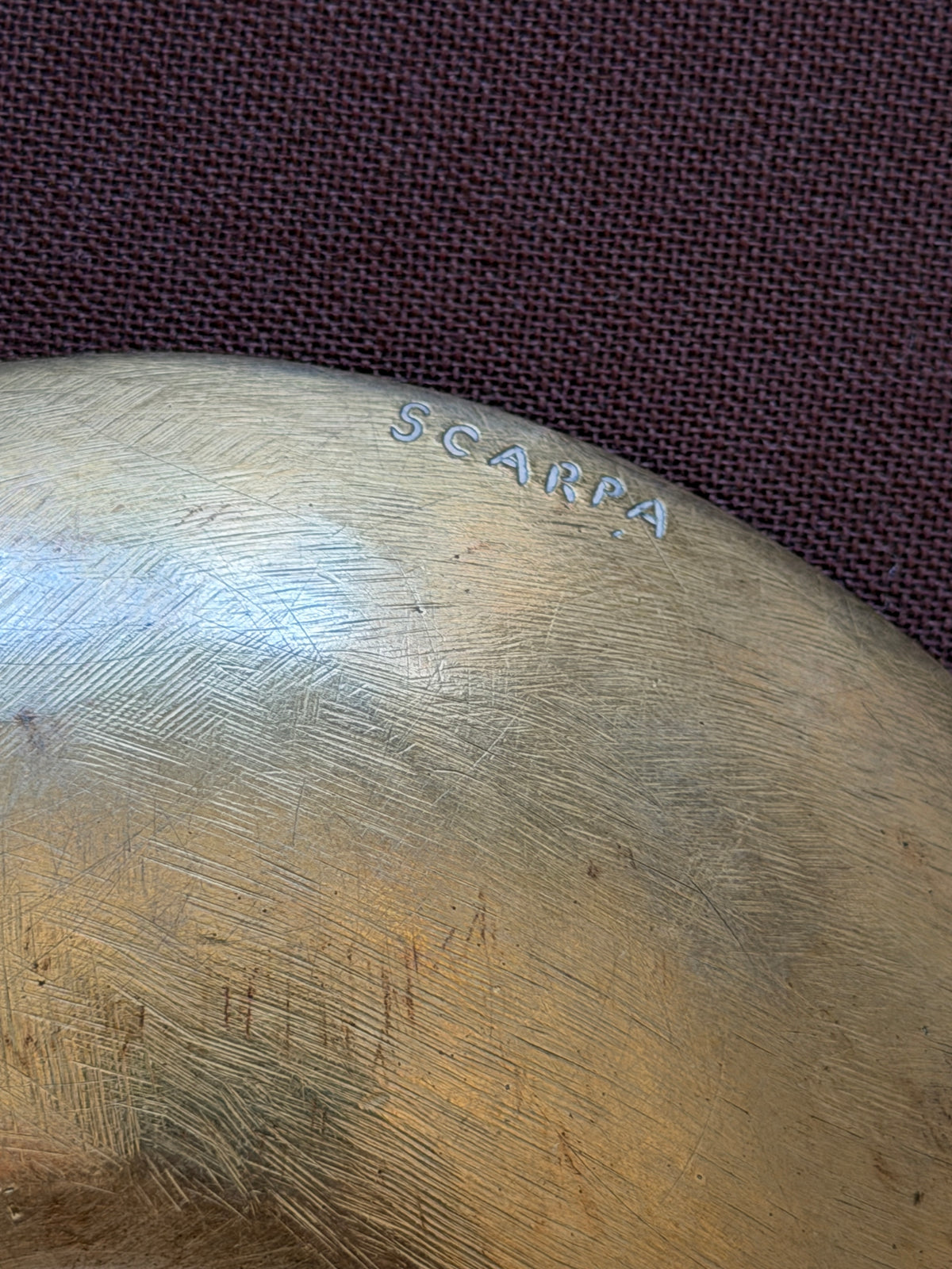 Underside of the bronze bowl showing the incised SCARPA signature near the rim and fine brushed tool marks