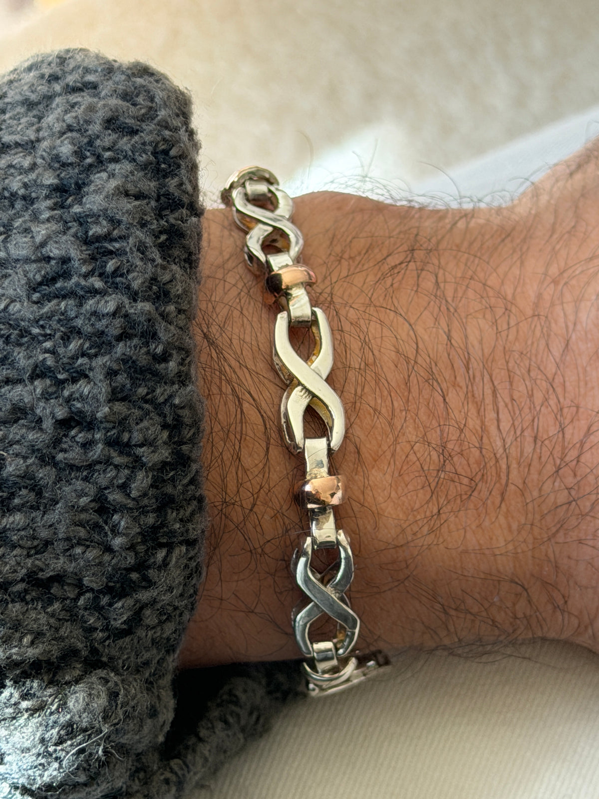 Close wrist view of the infinity bracelet, the sculpted silver figure eights and the polished gold rondelle between them