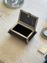 Black stone box with its hinged lid open, revealing the stone panel inside the lid, the silver tone rim, and a dark lined interior