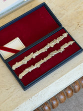 Open presentation box showing two rows of silver car-shaped place card holders on red velvet, with a ribbon-tied card in the corner