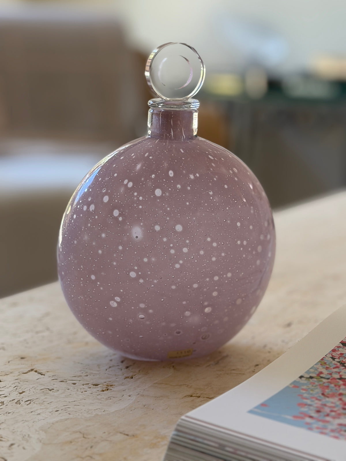 Close view of the lilac Murano decanter showing the dense white speckling across the glass and the maker label near the foot