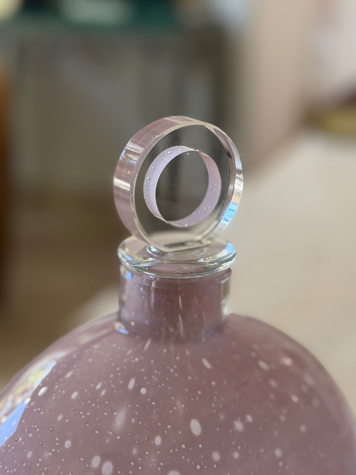 Close up of the Barbini stopper, a thick clear glass disc enclosing a lilac ring with tiny trapped bubbles