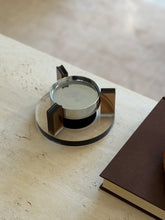 Angled overhead view of the floating ashtray highlighting the grooved tops of the amber uprights that serve as cigarette rests