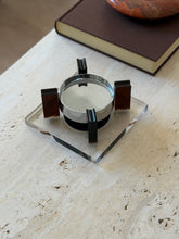 Amber Lucite and chrome magnetic floating ashtray on a square clear Lucite base, four amber uprights surrounding the mirror-polished chrome bowl