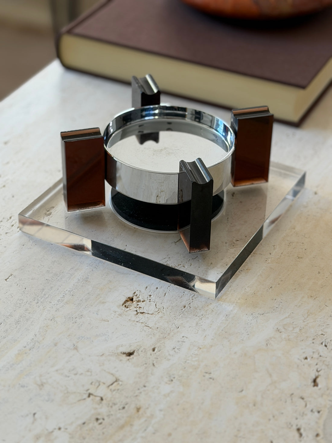Low angle close view of the square base floating ashtray showing the grooved cigarette rests atop the amber supports and the gap beneath the bowl