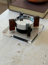 Low angle close view of the square base floating ashtray showing the grooved cigarette rests atop the amber supports and the gap beneath the bowl