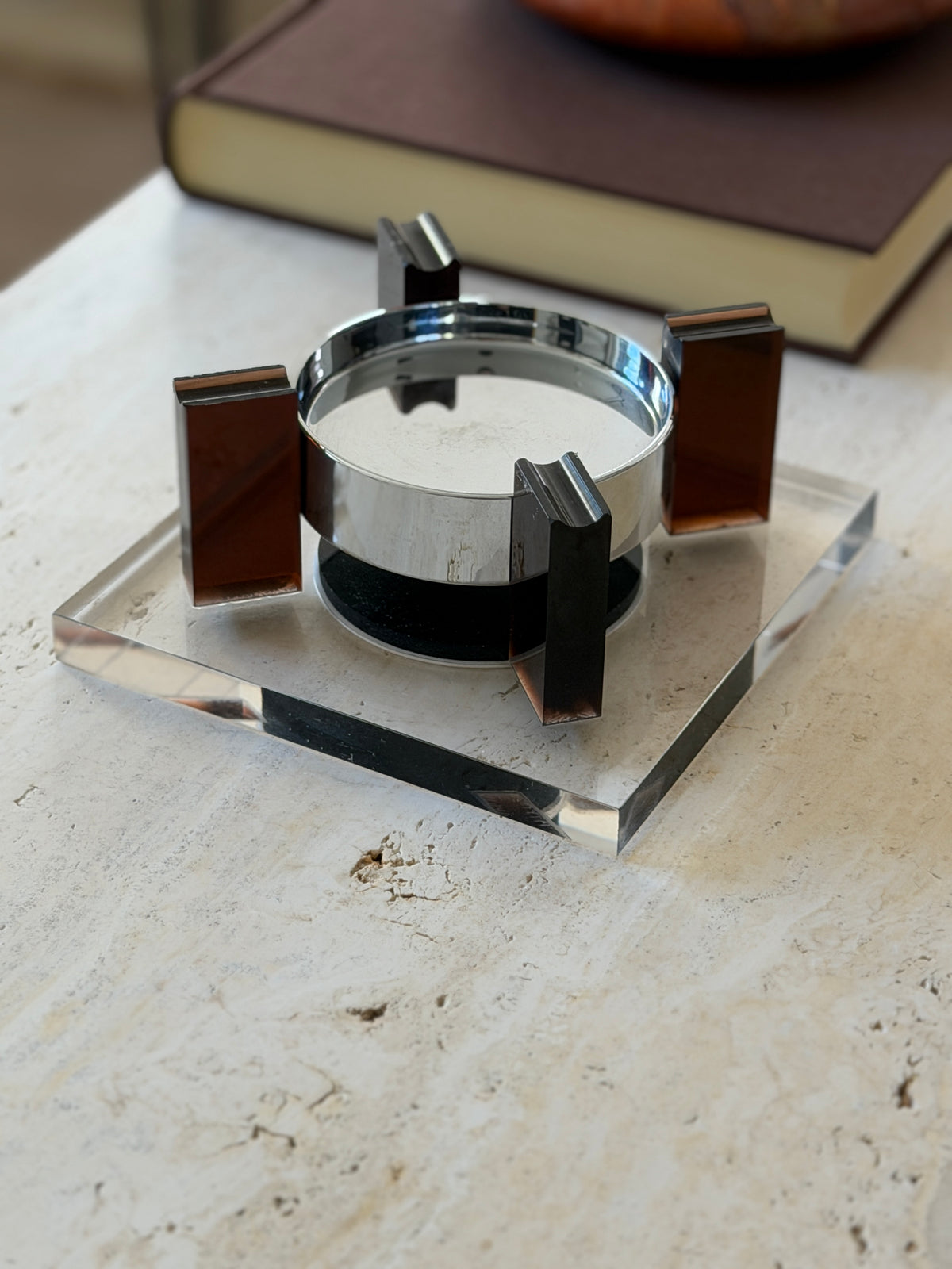 Low angle close view of the square base floating ashtray showing the grooved cigarette rests atop the amber supports and the gap beneath the bowl