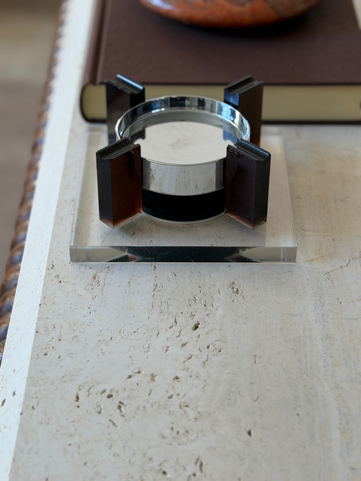 Straight-on view of the 1970s floating ashtray revealing the black magnetic base between two amber uprights and the beveled edge of the square Lucite base