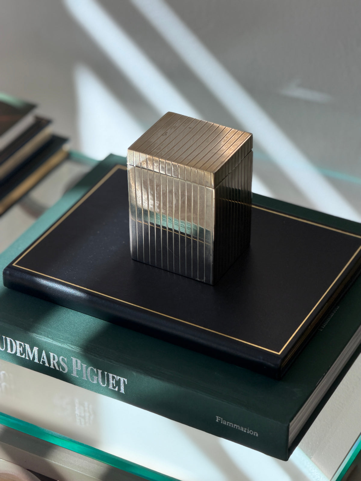 Angled perspective view of tall silver plated cedar-lined box displayed on dark green book from Collectors Gene