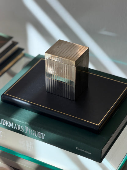 Angled perspective view of tall silver plated cedar-lined box displayed on dark green book from Collectors Gene
