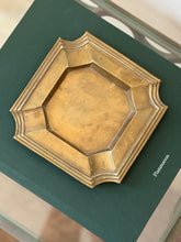 Top-down view of heavy brass geometric catchall dish with stepped borders styled on green book at Collectors Gene
