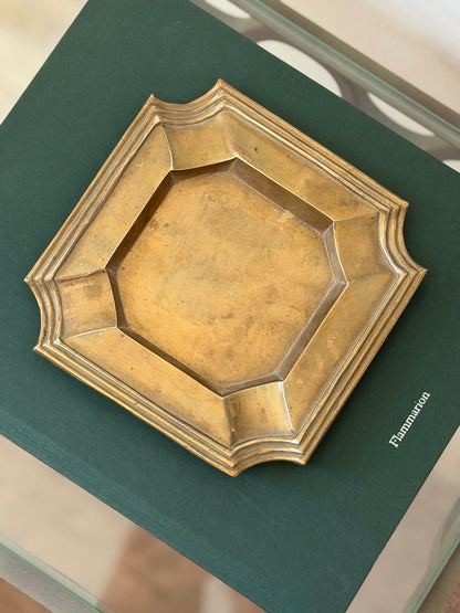 Top-down view of heavy brass geometric catchall dish with stepped borders styled on green book at Collectors Gene