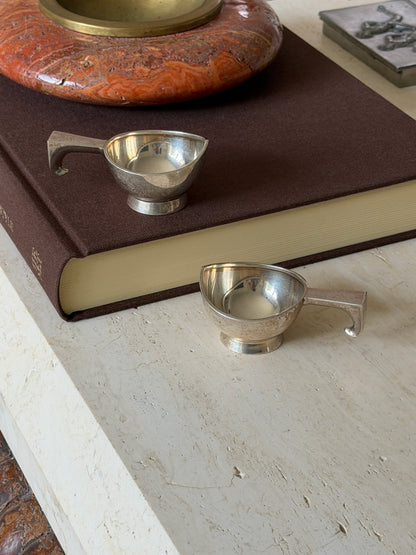 One dish set on top of a book while the second sits below it on the stone surface, both shown together in a styled arrangement