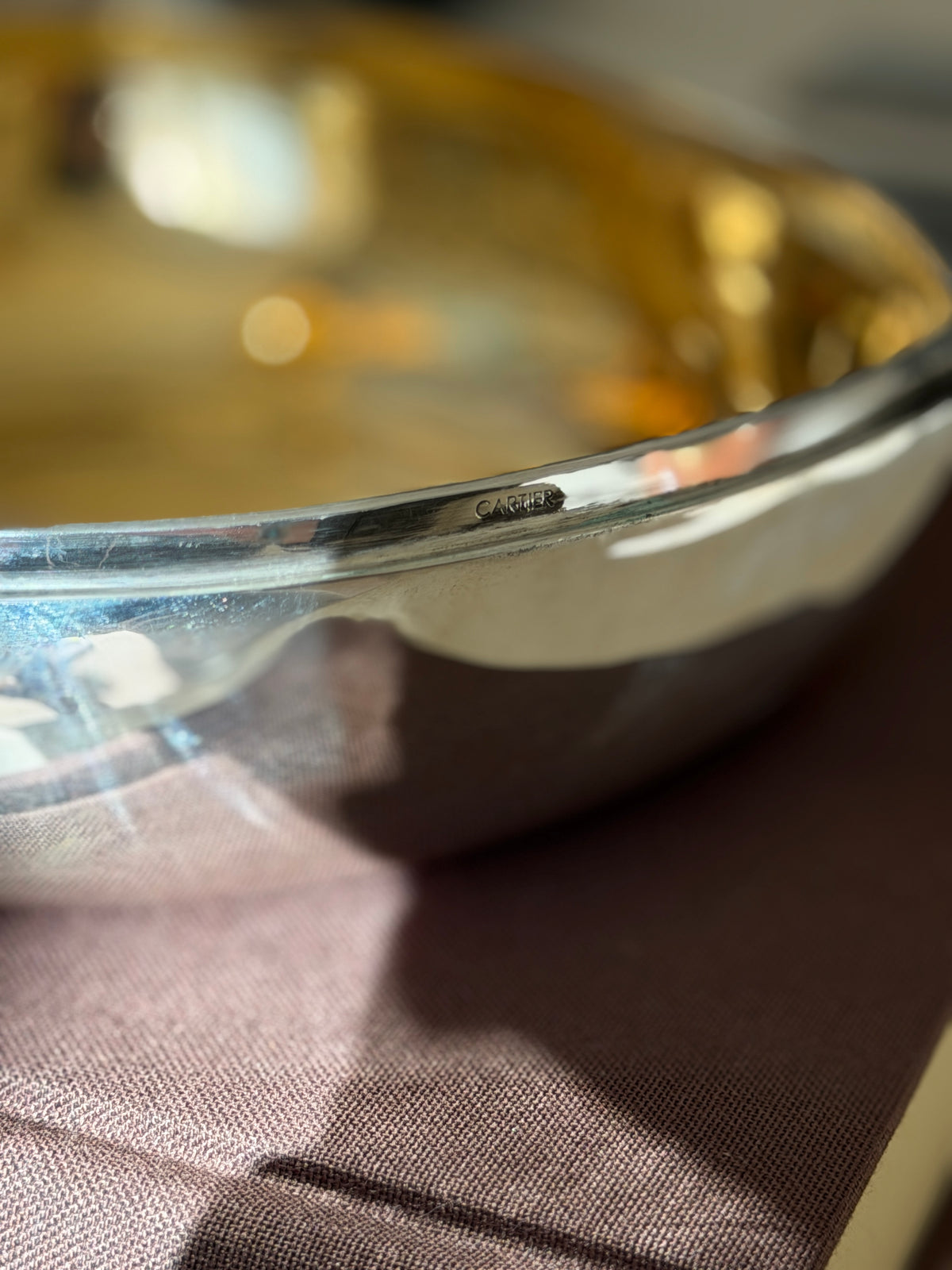 Close up of the CARTIER stamp on the outer rim of the sterling silver chestnut box, the gilt interior glowing behind