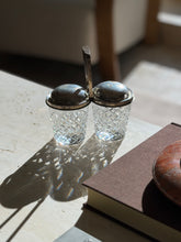 Backlit Cartier jam pot with sun shining through the hobnail cut crystal, the worn patina visible on the domed sterling lids