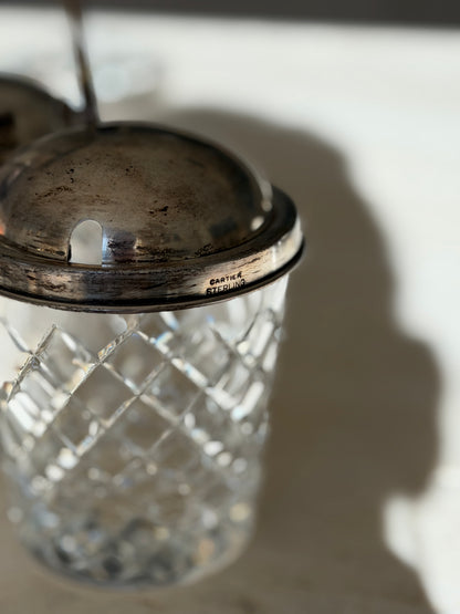 Close up of the jam pot rim stamped CARTIER STERLING beside the spoon slot, above the diamond cut crystal jar