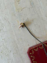Close-up of one spiked end of the chain, showing the tricolor gilt rings and pointed tip, with the box visible behind
