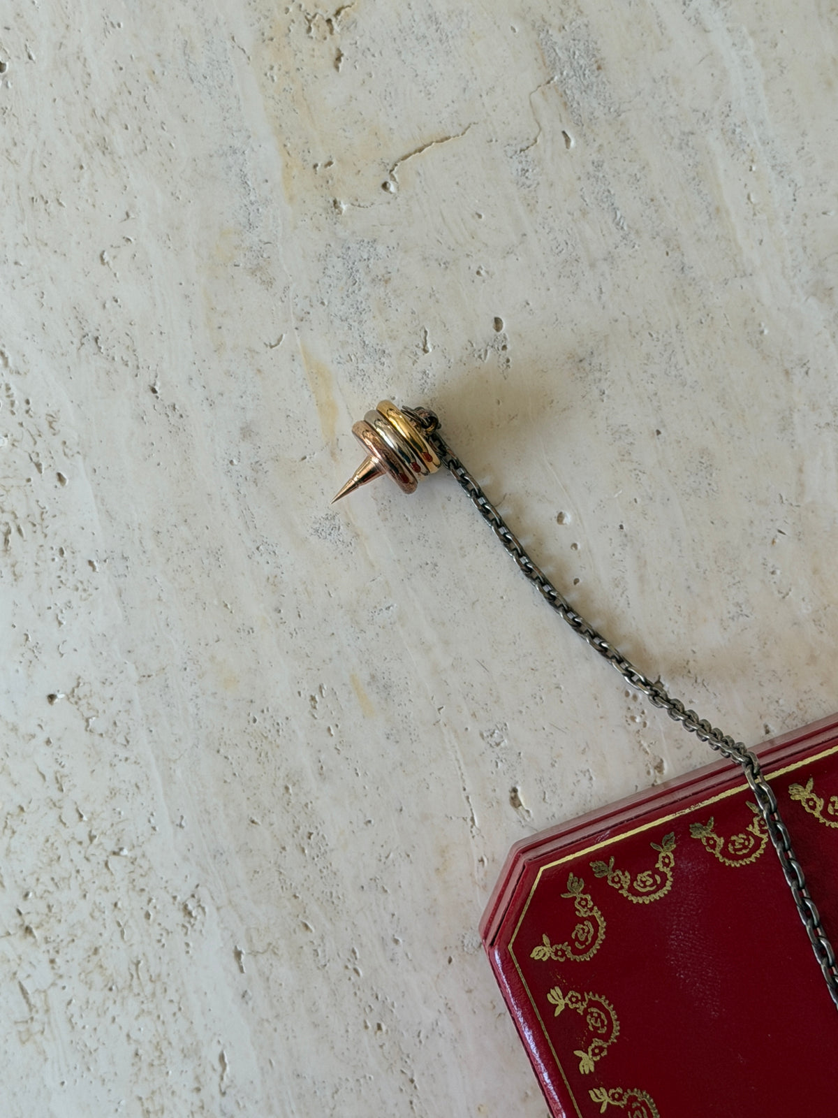 Close-up of one spiked end of the chain, showing the tricolor gilt rings and pointed tip, with the box visible behind