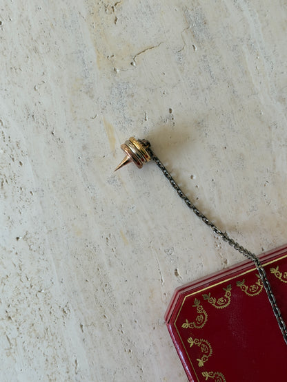Close-up of one spiked end of the chain, showing the tricolor gilt rings and pointed tip, with the box visible behind