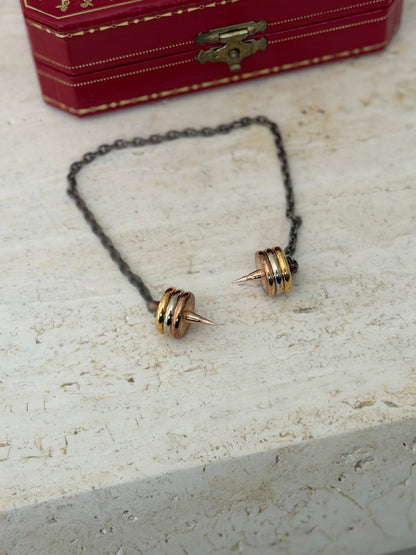 Both spiked ends of the chain laid out in front of the closed box, showing the matching tricolor gilt rings on each end