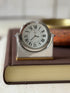 Front view of the Cartier desk clock showing twin sapphire cabochons on either side of the dial and the Swiss Made marking below the numerals