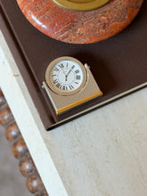 Overhead view of the Cartier desk clock on the corner of a book, showing the vertically fluted body and gold-tone banded base