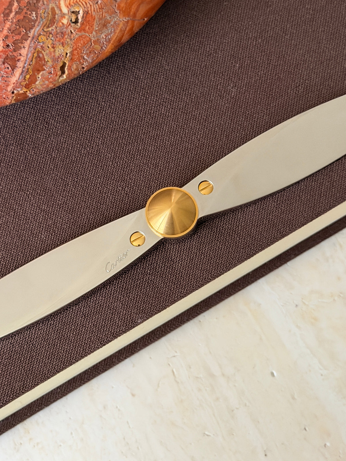 Close up of the propeller hub showing the brushed gold cone, two gold slotted screws, and the Cartier signature engraved on the polished blade