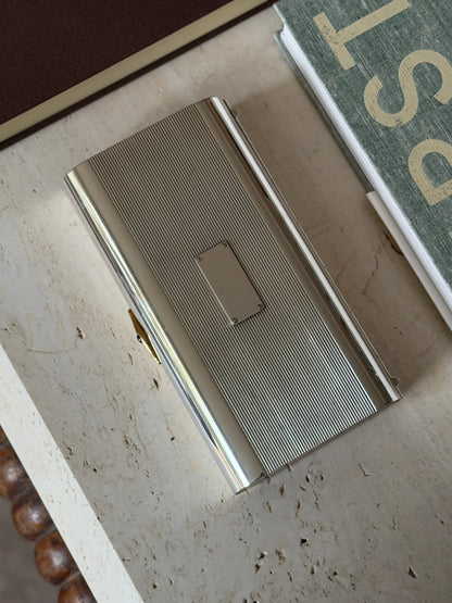 Overhead view of the wood cap end and gold clasp on the Cartier box, styled beside books