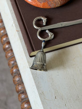 The bell displayed alongside the Hermes horse-head scissors on the same book, with the stone bowl visible above