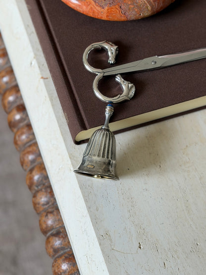 The bell displayed alongside the Hermes horse-head scissors on the same book, with the stone bowl visible above
