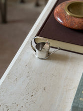 High angle view showing the full form of the silver miniature watering can dropper