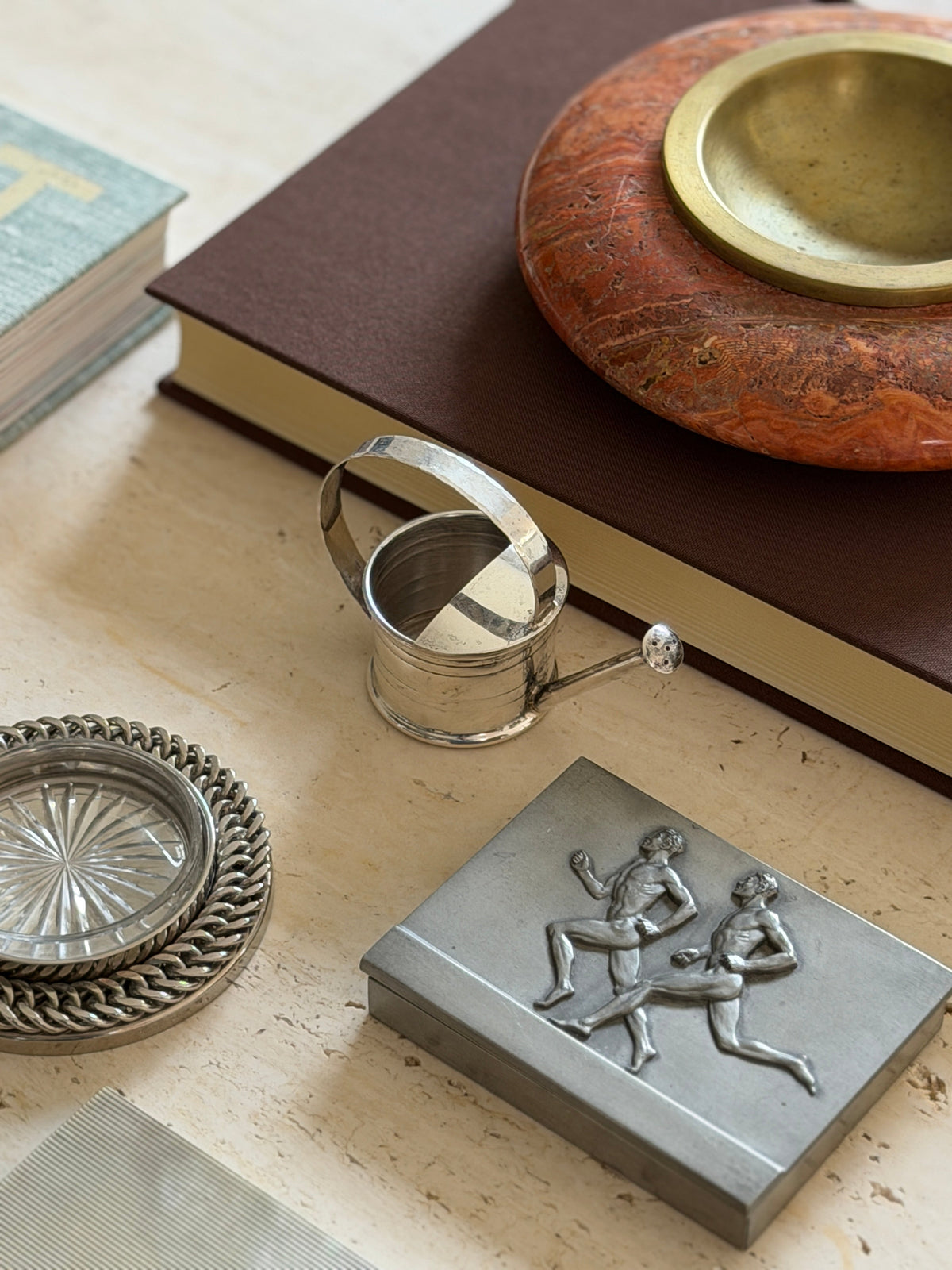 Styled tablescape view of the Cartier vermouth dropper with a pewter box, crystal coaster, and marble dish