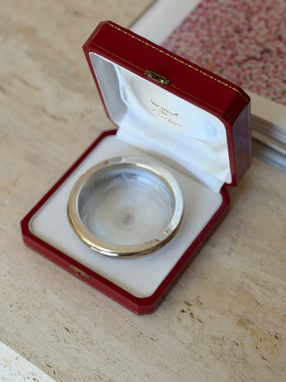 Open Cartier box revealing the Les Must de Cartier satin lining and the crystal dish with its gold and silver Trinity collar nestled inside