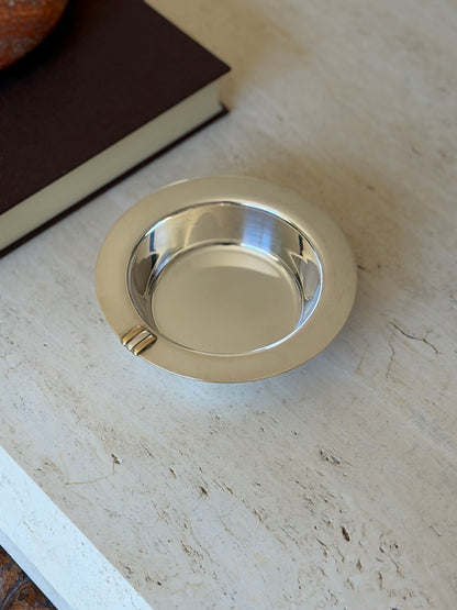 Cartier Trinity sterling silver bottle coaster with a wide flat rim and polished well, a three gold and silver bar detail at the edge, on travertine