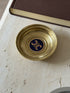 Closer straight-down view of the Triomphe medallion, showing the gold emblem clearly against the navy lacquer