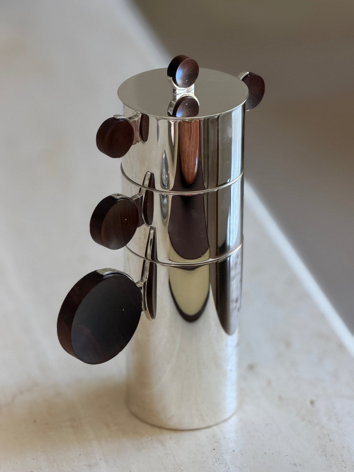 High angled view of the nested Gigogne coffee service showing the cascading rosewood disc handles down one side