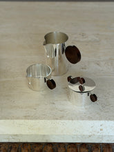 Side angle of the separated Gigogne coffee service pieces showing the interior silver bowls and rosewood handles