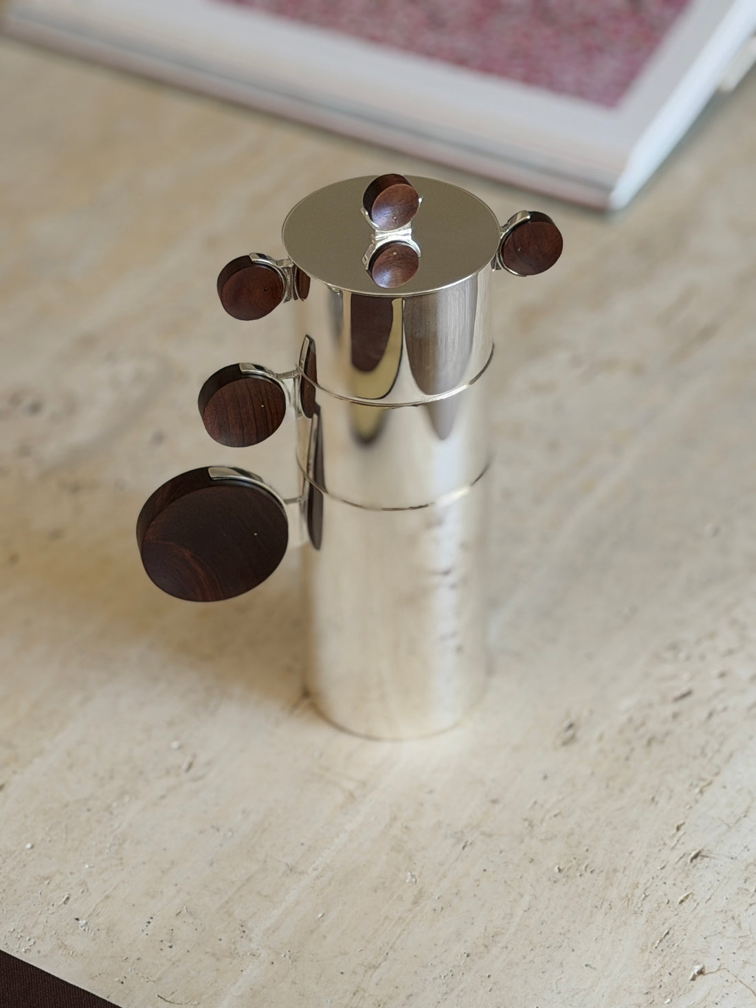 Nested Gigogne coffee service stack against a blurred pink art print in the background