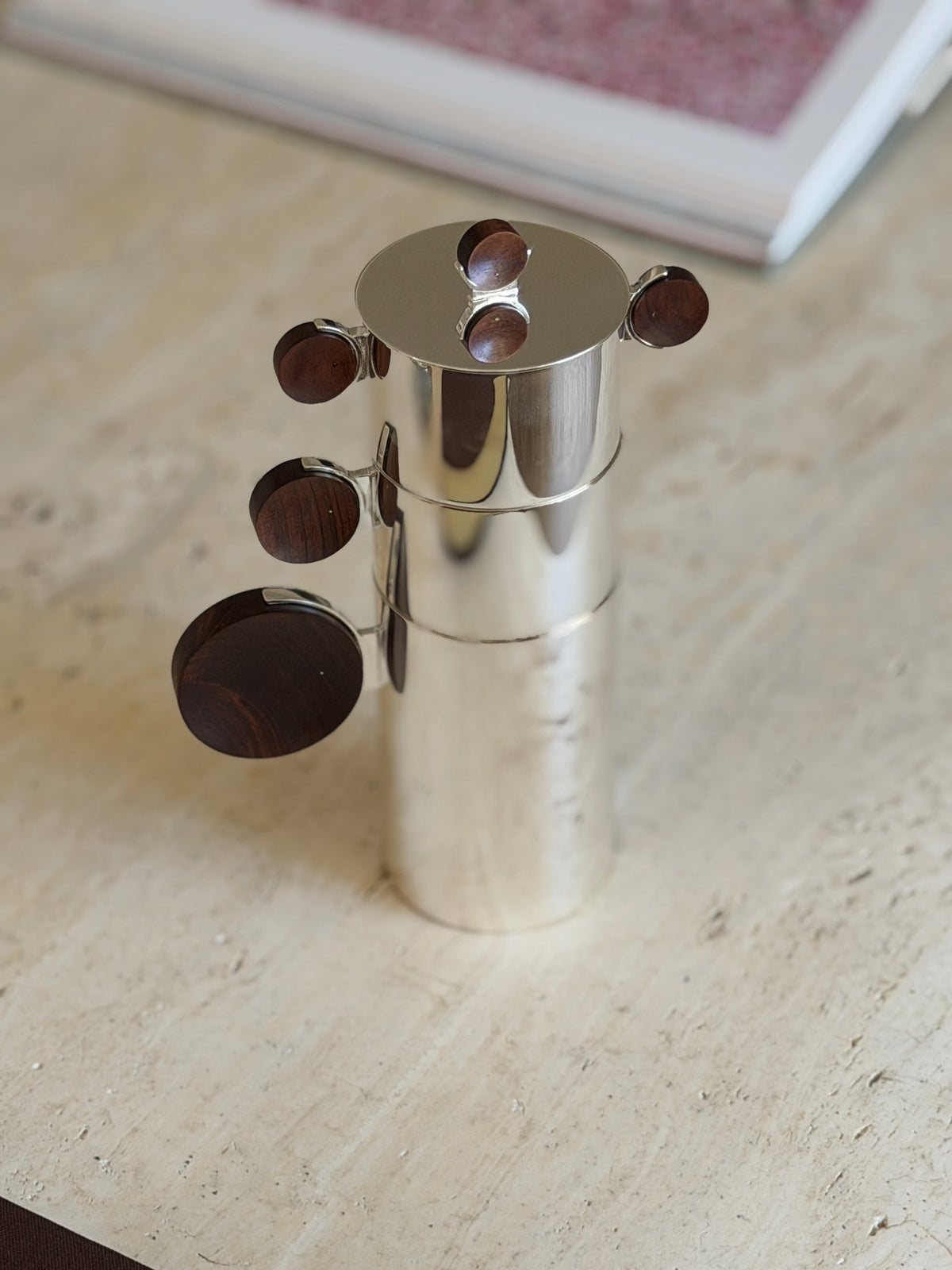 Nested Gigogne coffee service stack against a blurred pink art print in the background