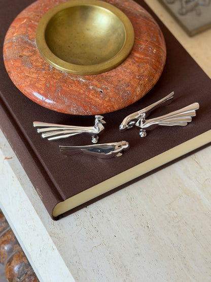 Christofle Gallia peacock and dove knife rests grouped together on a leather book