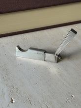 Dunhill cigar cutter opened on travertine, the engine turned lid raised and the curved guillotine slot exposed beside the sliding blade