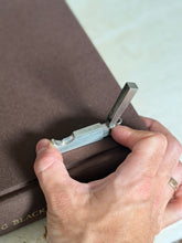 Hand holding the Dunhill travel cigar cutter open, showing its compact scale and the hallmarked silver frame