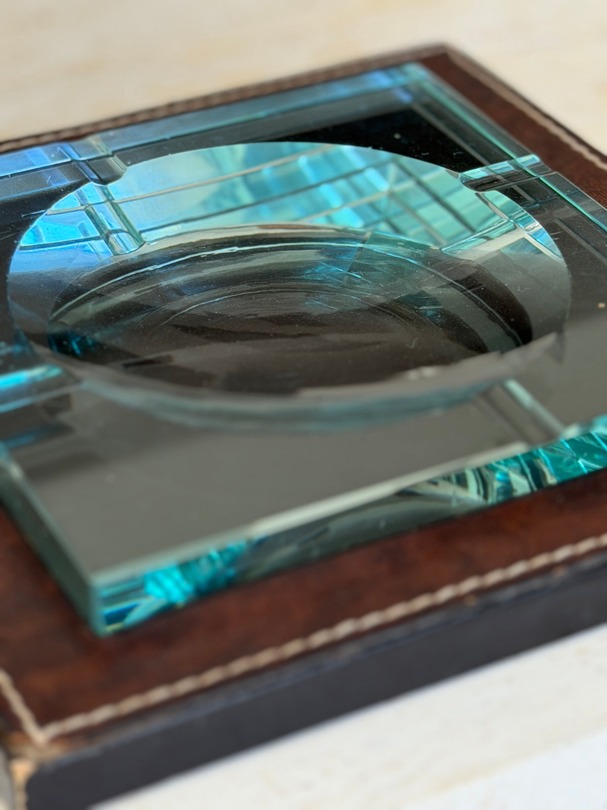Close-up corner view showing thick beveled teal glass edge and stitched leather surround available at Collectors Gene